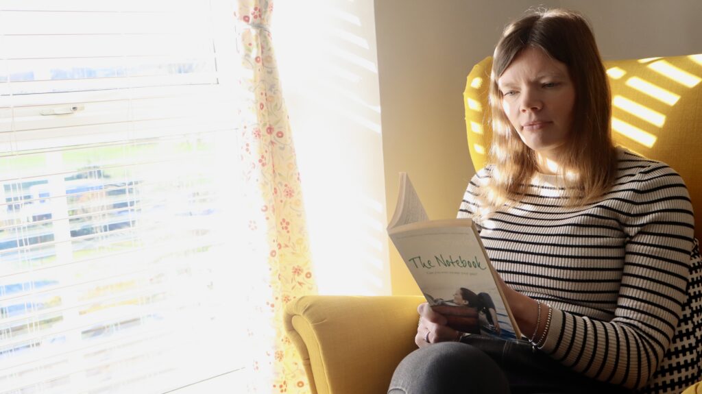 Foster carer Meleri reading a book by the window